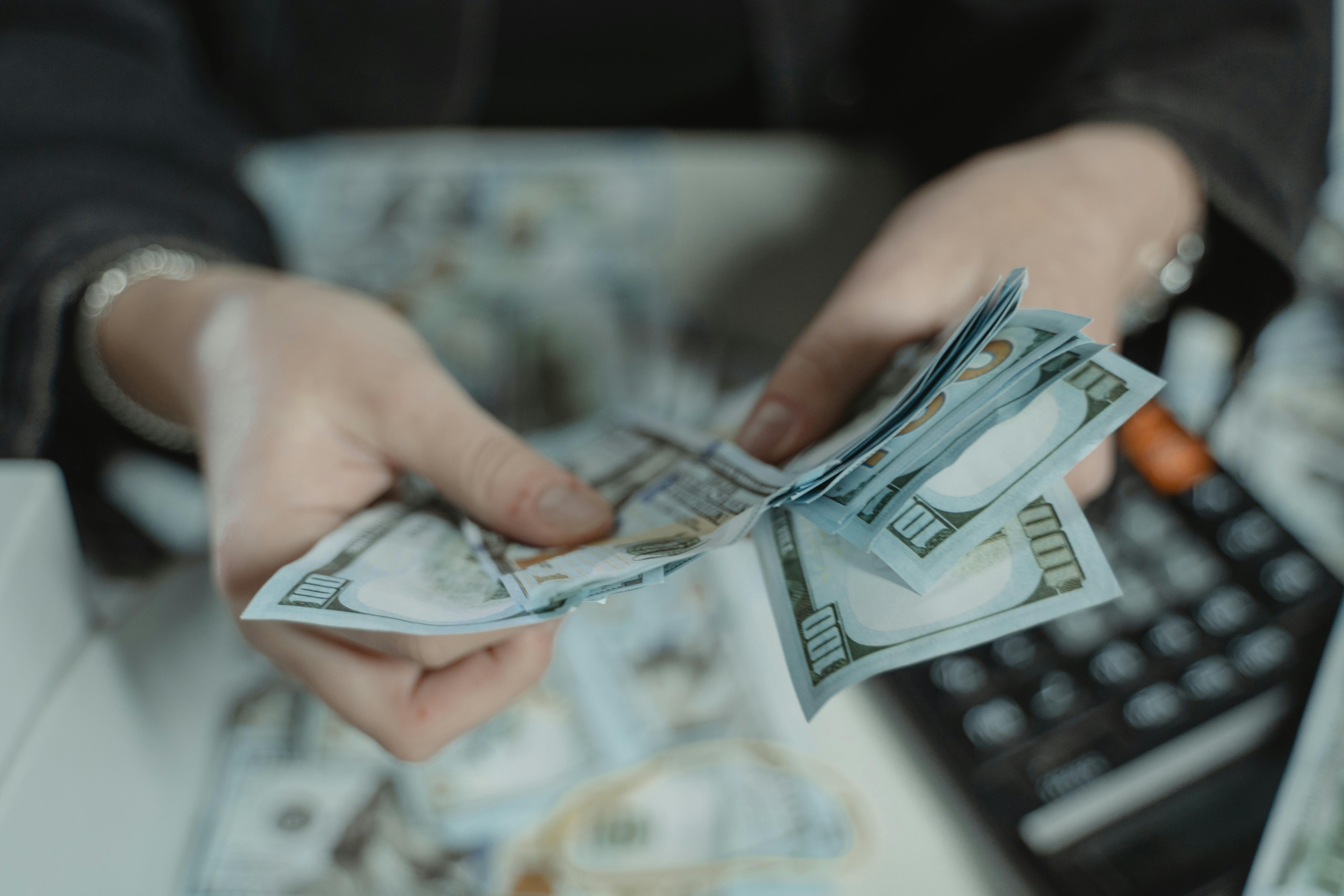 Person counting money with a calculator on the table in the background